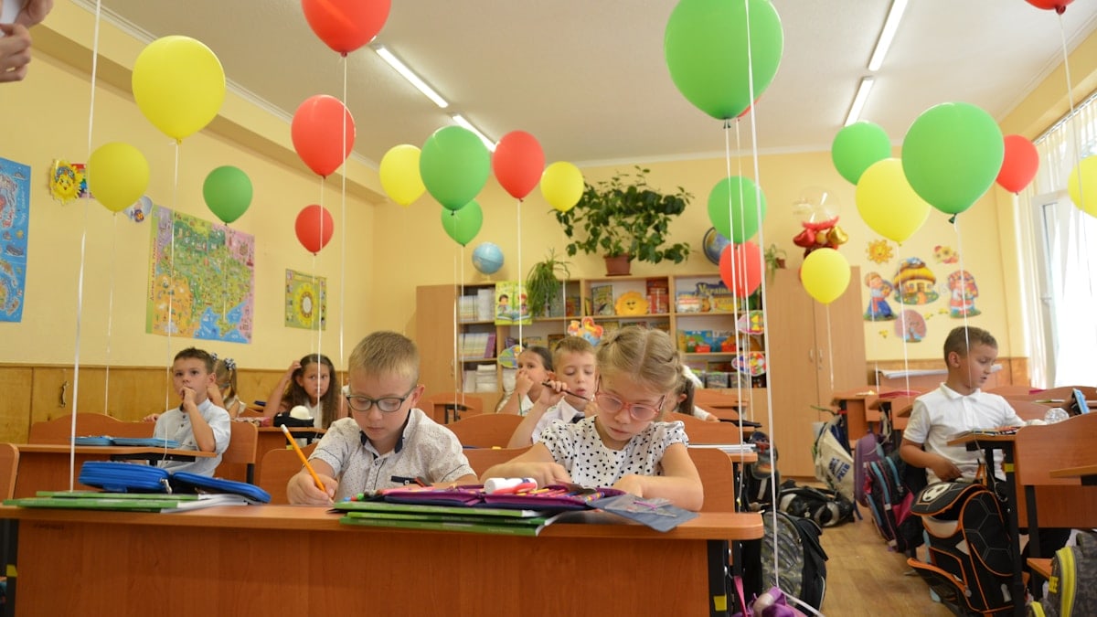 Two diverse elementary school children classmates studying together at desk
